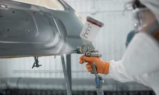 Technician spray painting car hood.
